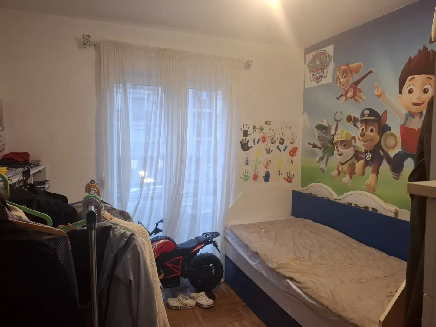 Dječija soba sa krevetom i tapetom sa crtanim likovima.