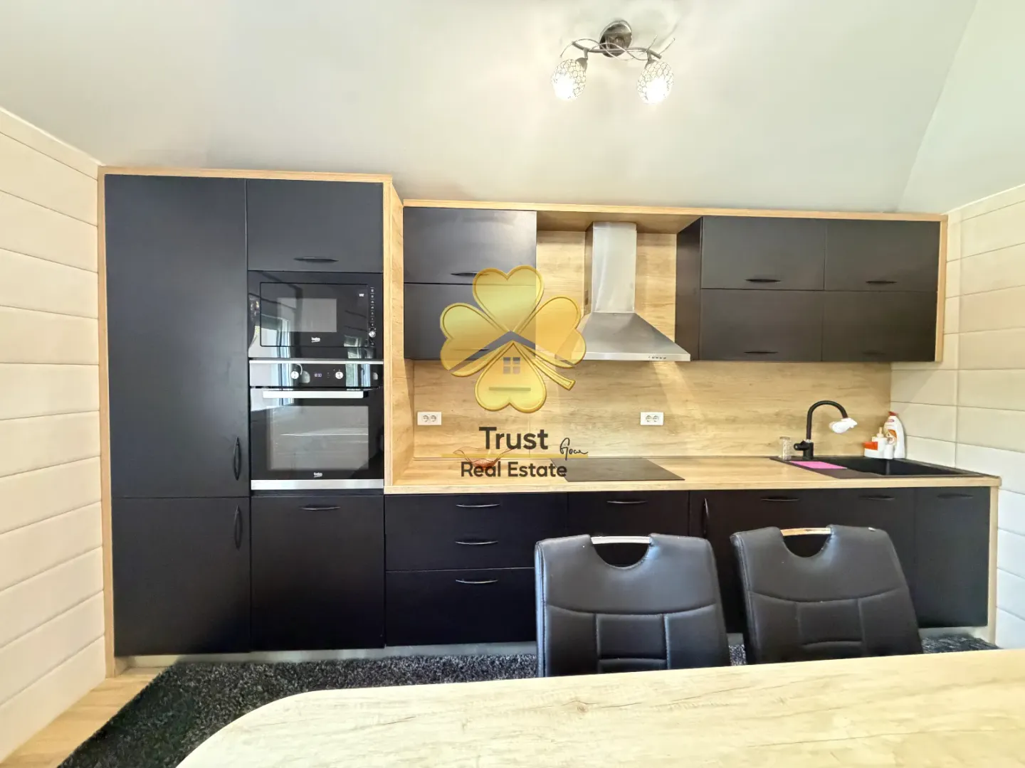 Modern kitchen with dark cabinetry and wooden details.