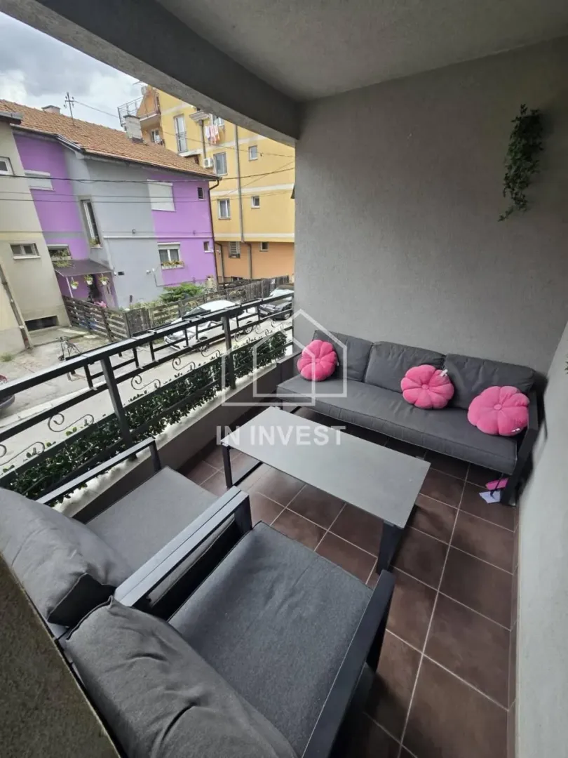 Namešten balkon sa garniturom za sedenje i pogledom na ulicu.