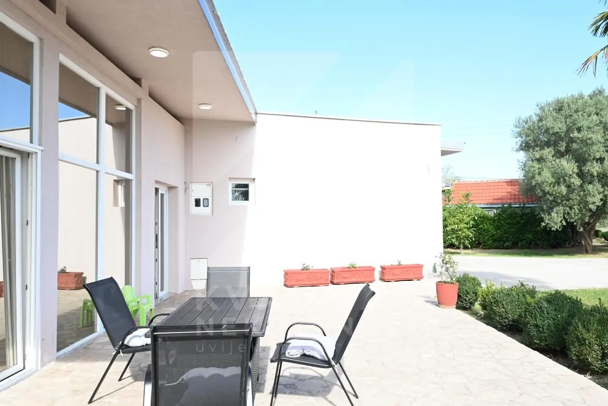 Covered terrace with a table and chairs in front of the house.