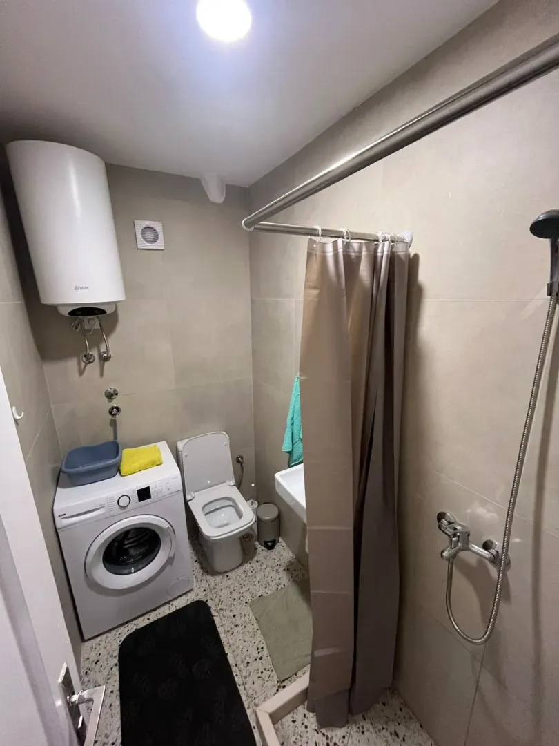 Smaller bathroom with a shower, washing machine, and water heater.