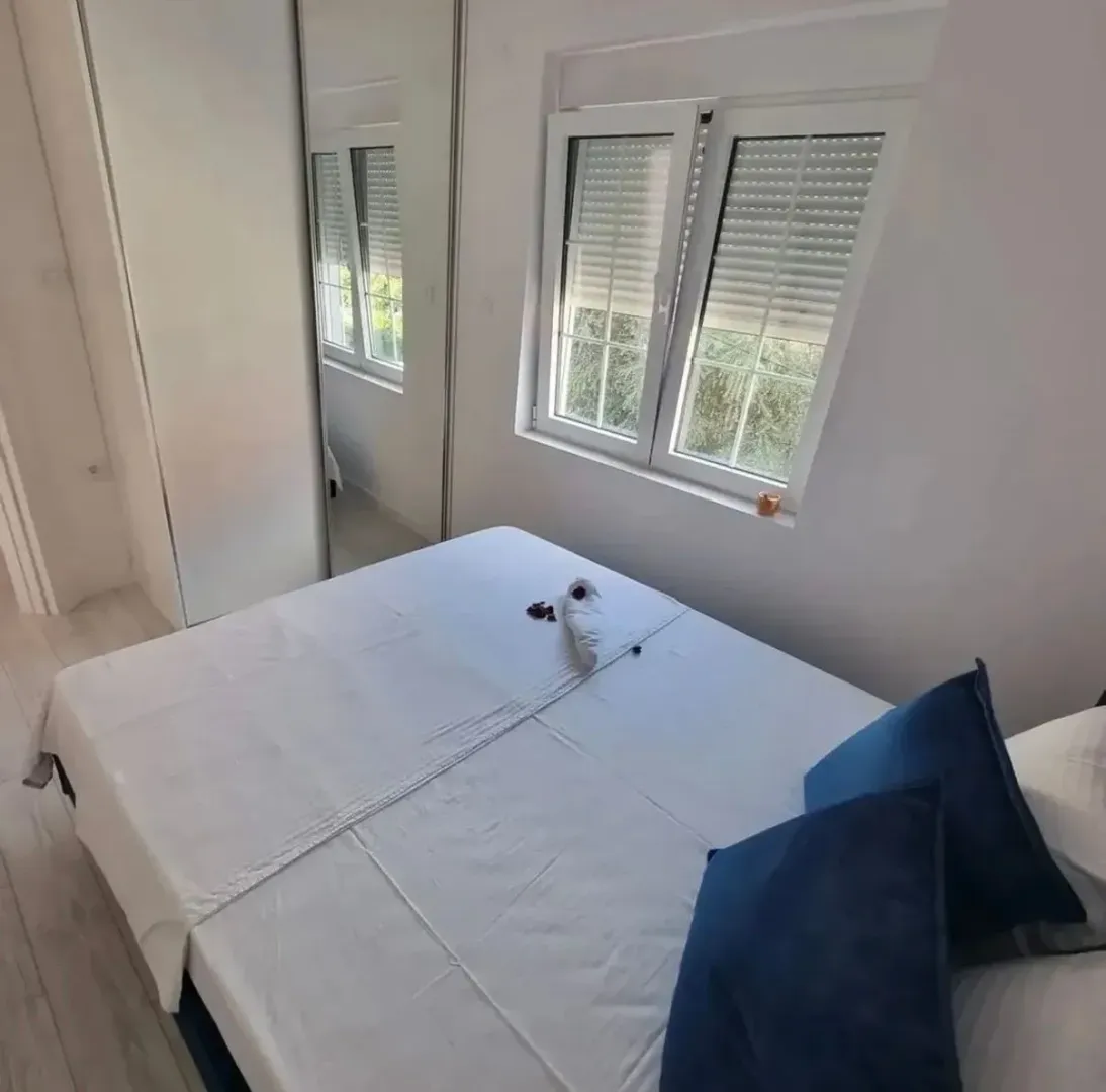 Bright bedroom with a double bed, mirrored wardrobe, and a window.