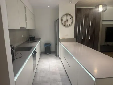 Modern kitchen with white cabinetry and a breakfast bar. - image 12
