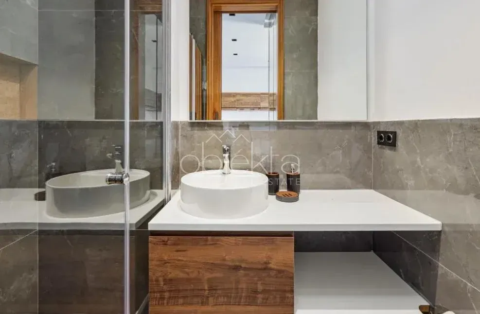 Modern bathroom with a countertop washbasin, mirror, and shower enclosure.