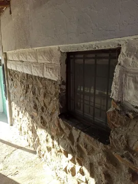 Pogled na kamenu fasadu kuće sa prozorom i rešetkama. - image 8