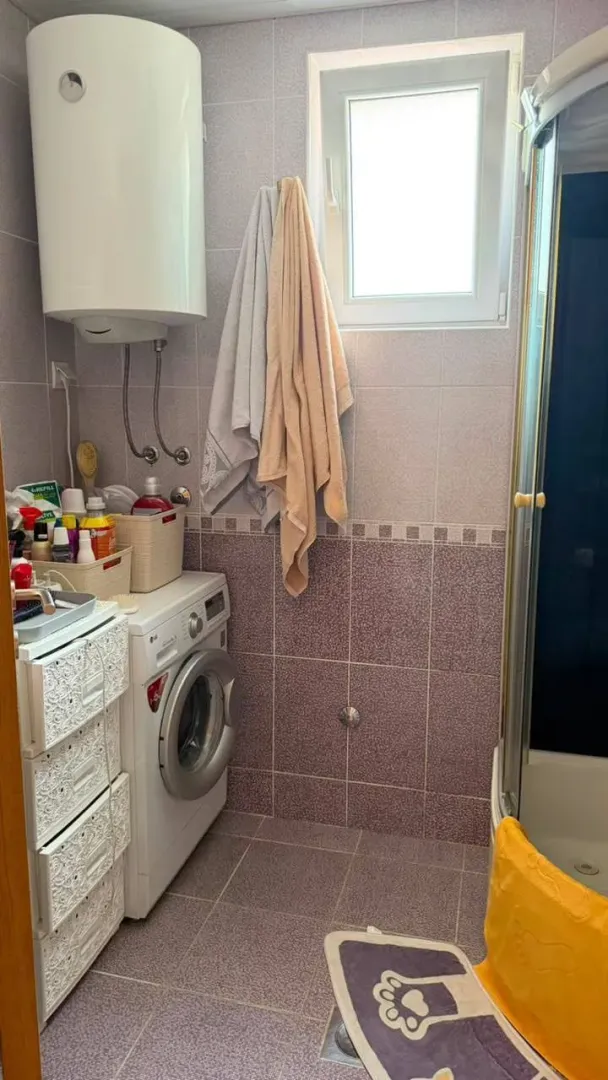 Small bathroom with a shower cabin, washing machine, and water heater.