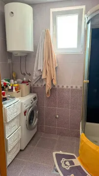 Small bathroom with a shower cabin, washing machine, and water heater. - image 7