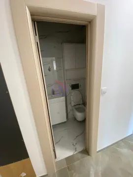 Pogled iz hodnika na manje kupatilo sa sanitarijama i bijelim ormarićem. - image 5