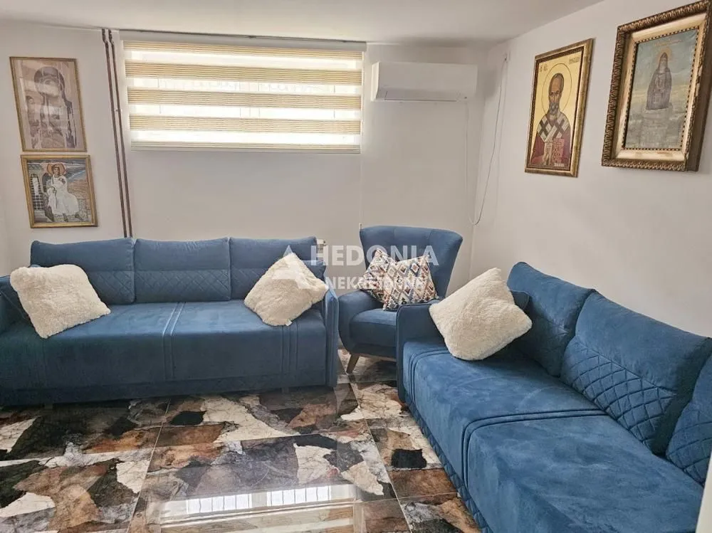 Dnevni boravak opremljen plavim garniturama i detaljima na zidovima.