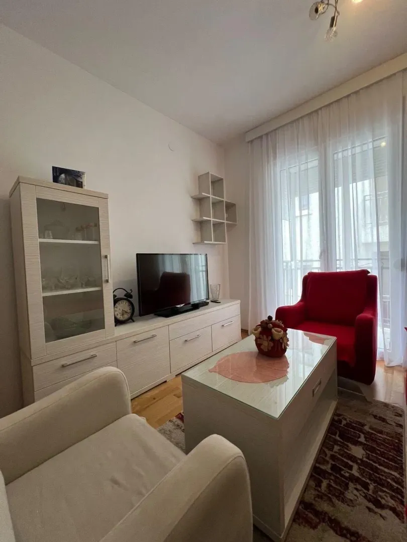 Living room with seating furniture, TV unit and display cabinet.