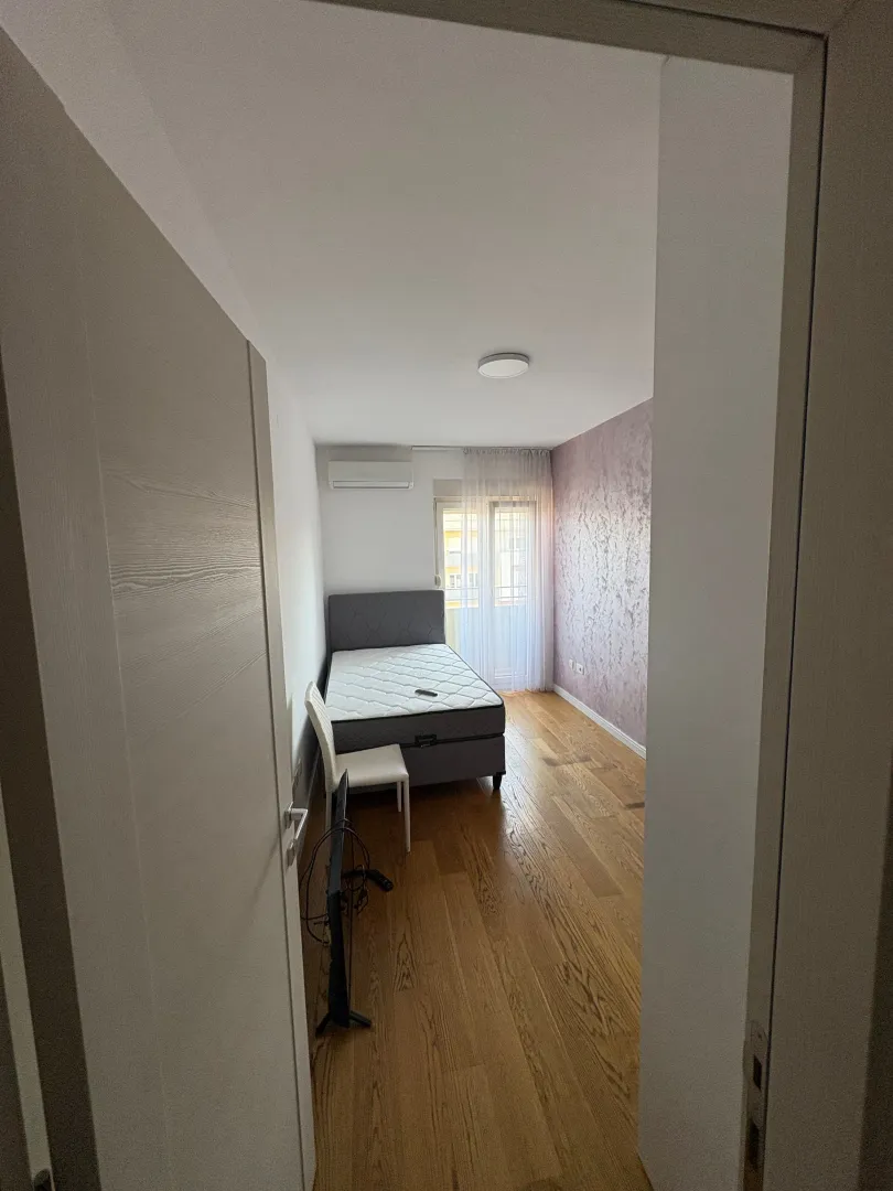 View from the hallway into the bedroom with a bed and hardwood floors.