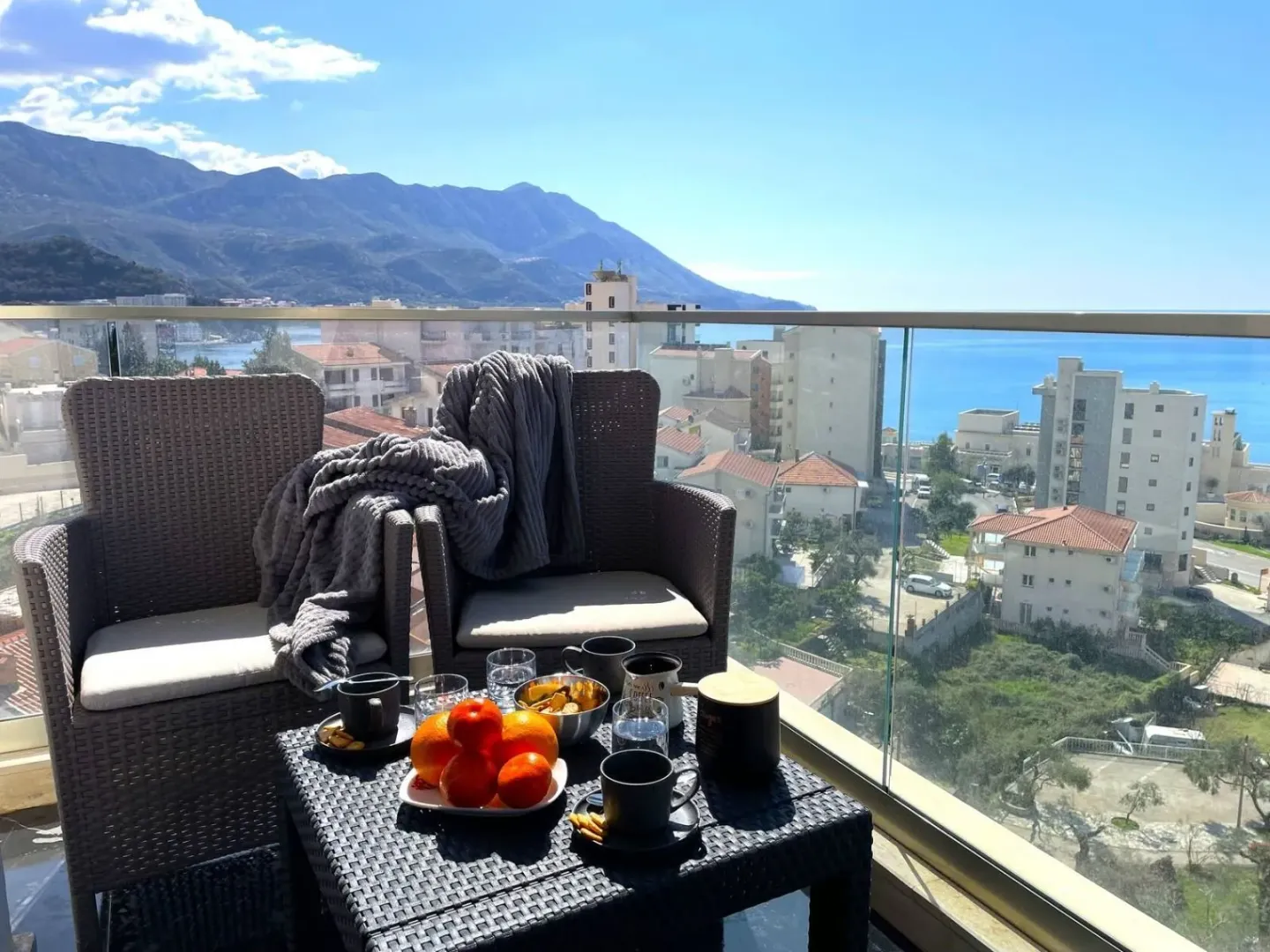 Furnished balcony with seating set and view of the sea and the city.