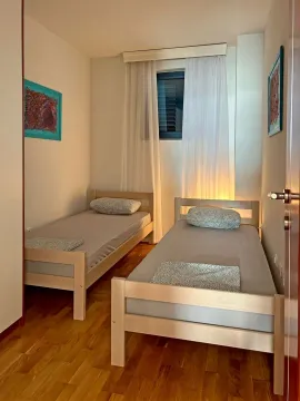 Spavaća soba sa dva odvojena kreveta i drvenim podom. - image 10
