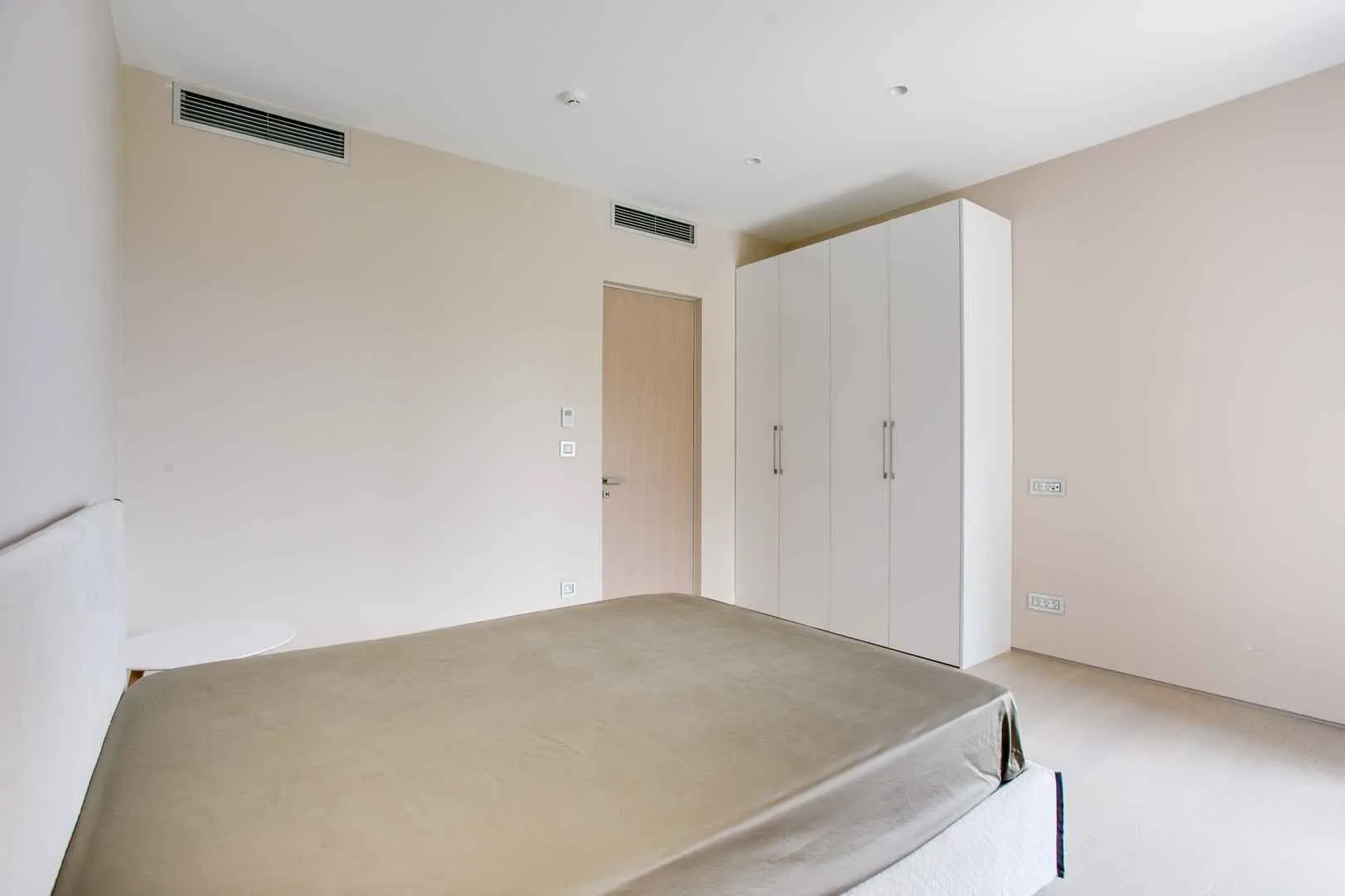 Svijetla spavaća soba sa bijelim garderoberom i modernim krevetom.
