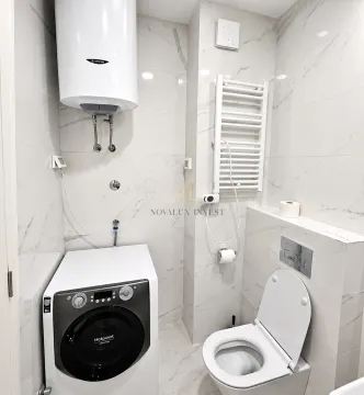 Kupatilo sa wc šoljom, veš mašinom i bojlerom na zidu. - image 9