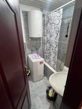 Small bathroom with a bathtub, washbasin, water heater, and washing machine. - image 7