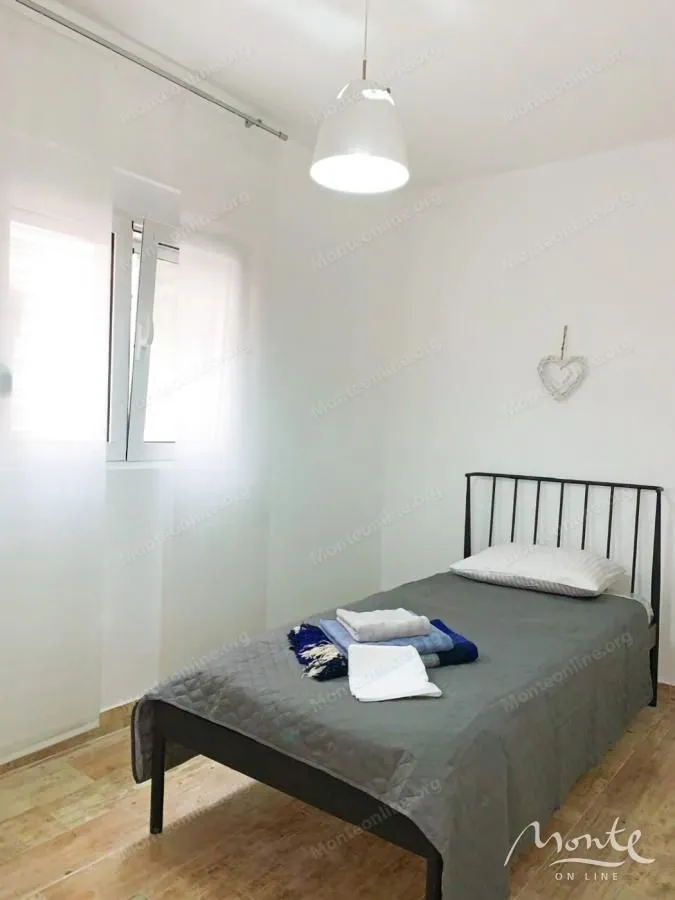 Manja spavaća soba sa krevetom za jednu osobu i bijelim zidovima.