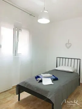 Manja spavaća soba sa krevetom za jednu osobu i bijelim zidovima. - image 12