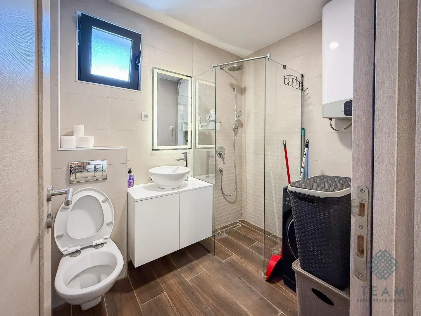 Modern bathroom with a walk-in shower, washbasin, and toilet.