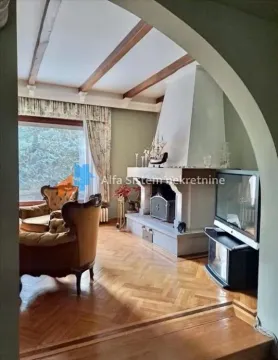 Living room with a fireplace, wooden ceiling beams, and seating furniture. - image 6