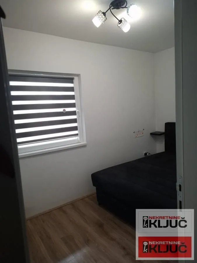 Pogled na manju spavaću sobu sa krevetom i prozorom.