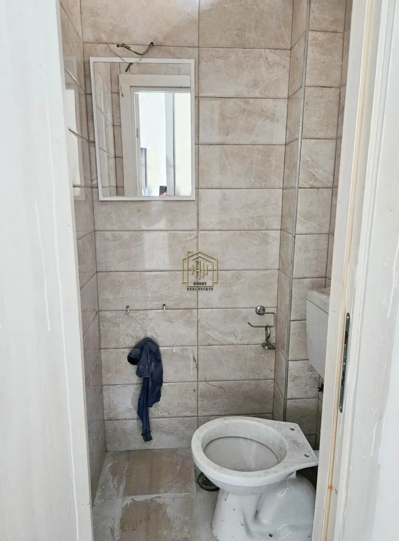 View of the bathroom with a toilet bowl and a wall mirror.