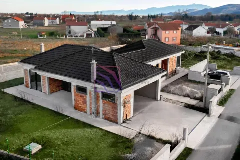 Pogled iz vazduha na prizemnu kuću u izgradnji sa crnim krovom i dvorištem. - image 7
