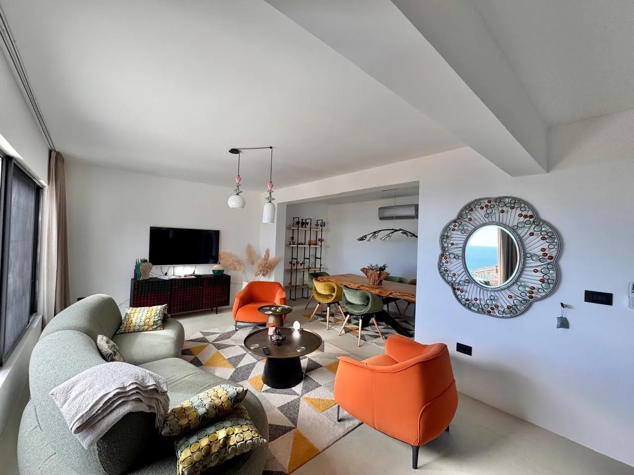 Spacious living room with a sofa, armchairs, and a dining area in the background.
