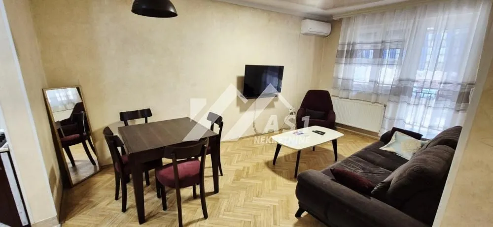 Dnevni boravak sa garniturom, trpezarijskim stolom i televizorom.