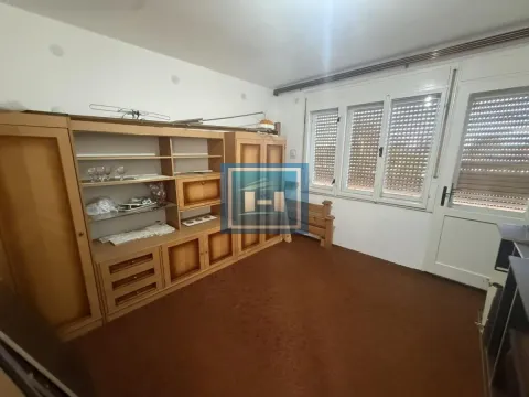 Living room with a large wooden cabinet and windows facing outside. - image 2