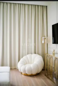 Dnevni boravak sa udobnom belom foteljom i elegantnim draperijama. - image 2