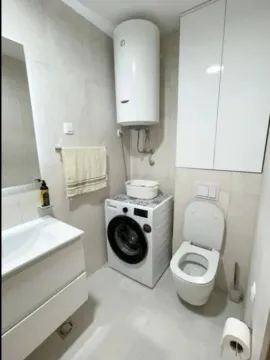 Compact bathroom with a sink, toilet, washing machine, and water heater. - image 4