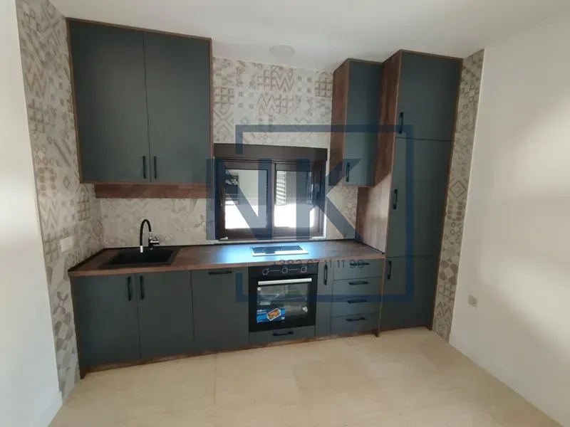 Modern kitchen with dark cabinetry, built-in oven, and a sink.