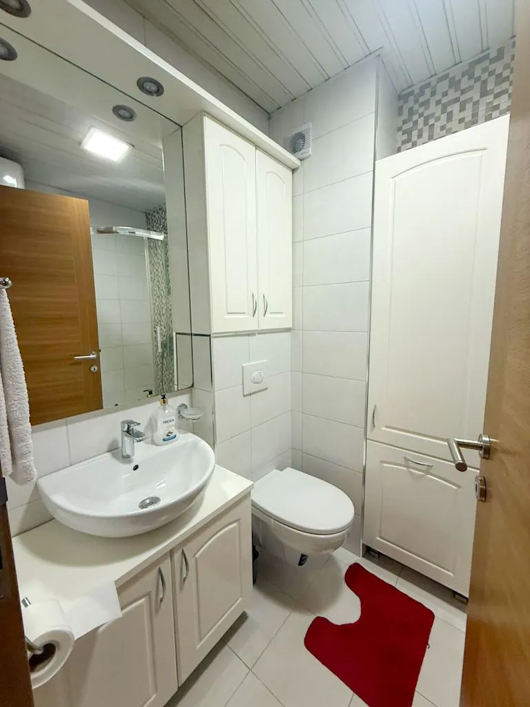 Small bathroom with white cabinetry, sink, and toilet.