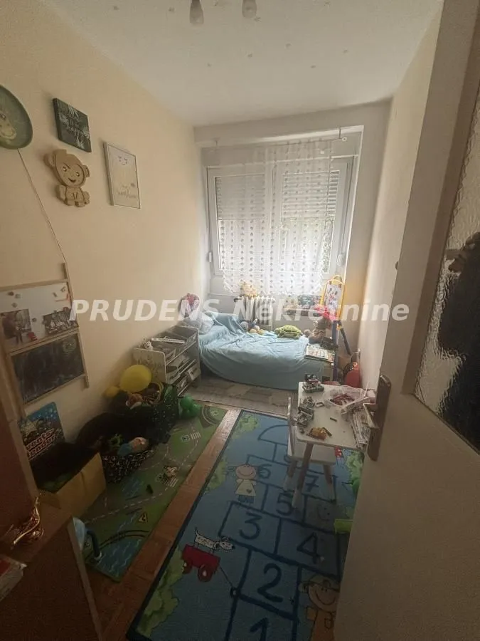 Dečja soba sa krevetom, igračkama i tepihom sa motivom igre.
