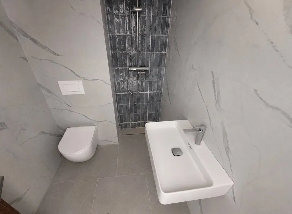Moderne kupatilo sa umivaonikom, WC šoljom i tuš kabinom.