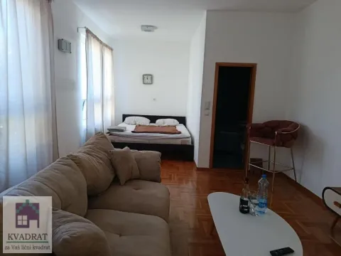 Living room with a sofa and a bed in the background. - image 2