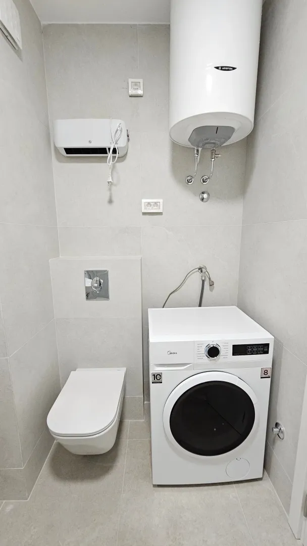 Small bathroom equipped with sanitary fixtures, water heater, and washing machine.