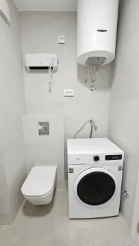 Small bathroom equipped with sanitary fixtures, water heater, and washing machine. - image 10