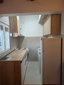 Small modern kitchen with wooden elements and a white refrigerator. - image 3