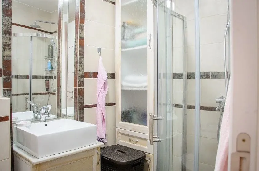 Compactly equipped bathroom with a washbasin, shower cabin, and cabinet.