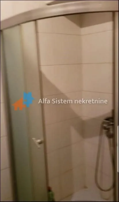 A shower cabin in a bathroom with white wall tiles.