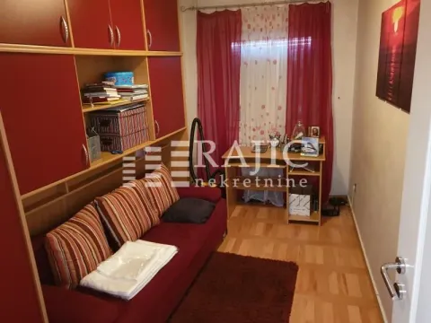 Living room with a red sofa, closets, and a desk. - image 9