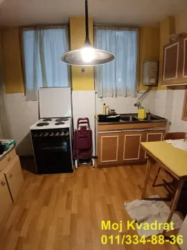 Starija kuhinja sa drvenim elementima, šporetom i sudoperom. - image 3