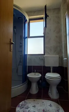 Simple bathroom featuring a shower cabin, bidet, and window. - image 14
