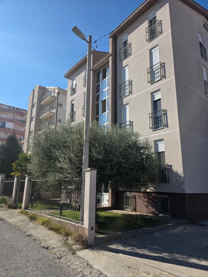 Exterior view of the residential building with a landscaped yard and fence.