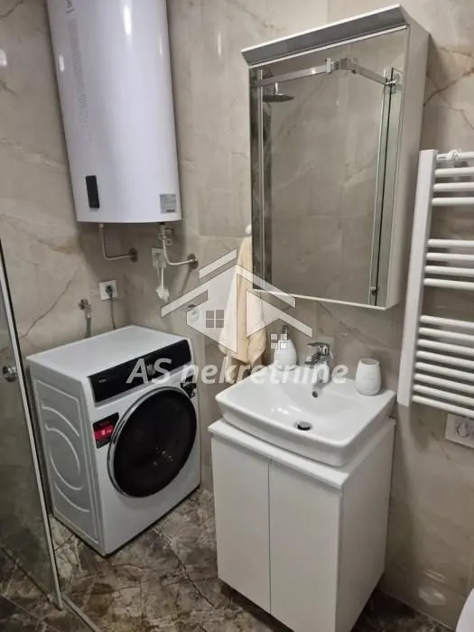 Compact bathroom with a sink, washing machine, and water heater.
