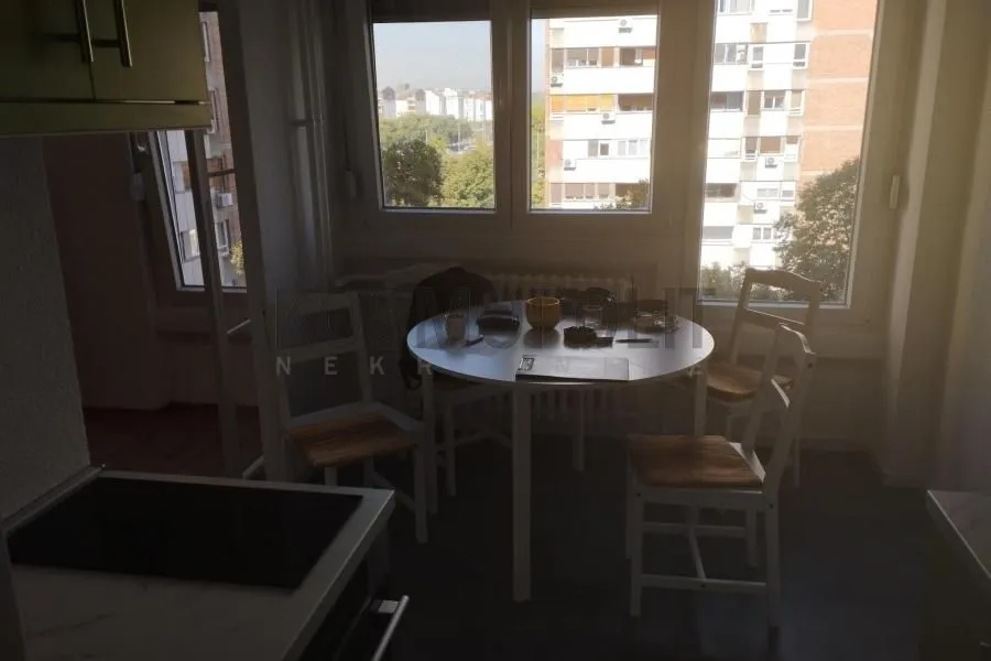 Kuhinja sa trpezarijskim stolom i prozorima.