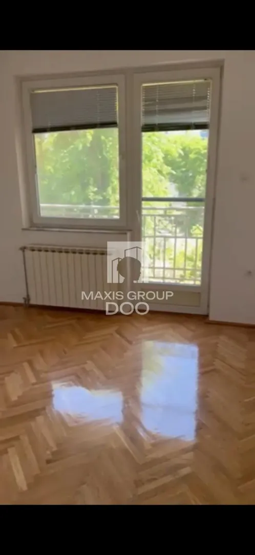 Prazna soba sa parketom i izlazom na terasu.