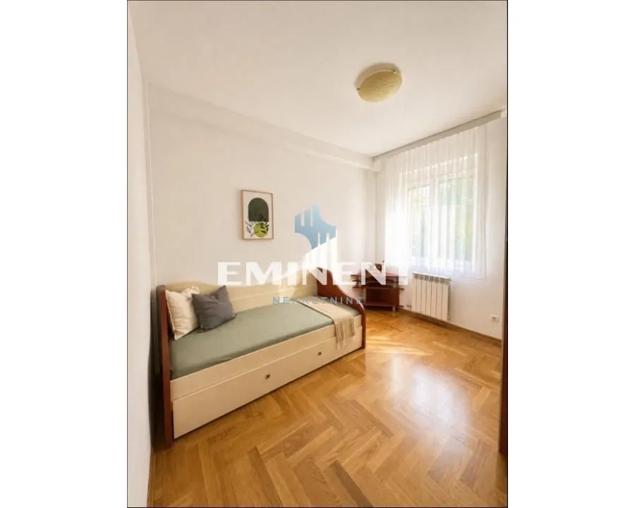 Furnished bedroom with a bed and parquet flooring.